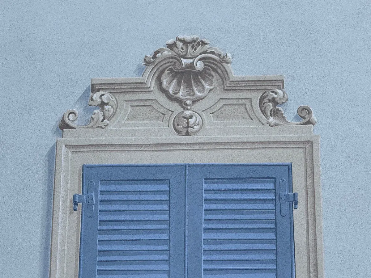 Finestra con gelosie azzurre e cornice barocca dipinte in trompe-l'œil