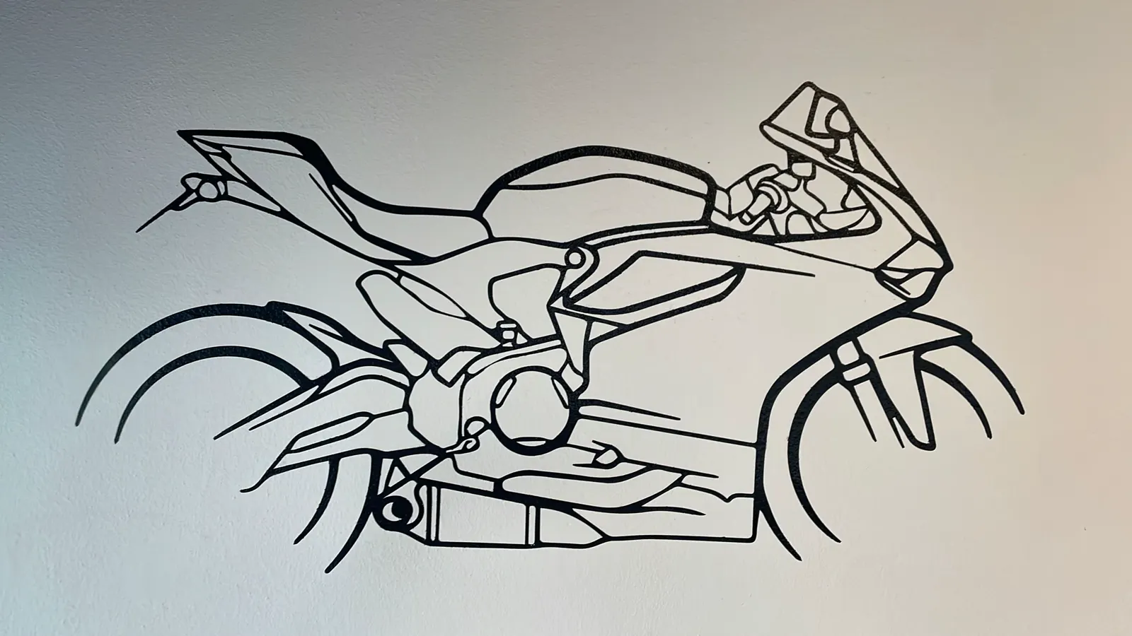 Disegno a linea nera di una moto Ducati su parete bianca