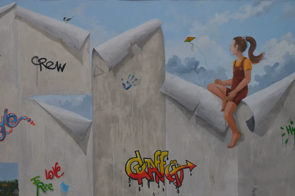 Ragazza seduta su un muro dipinto in trompe-l'œil con graffiti