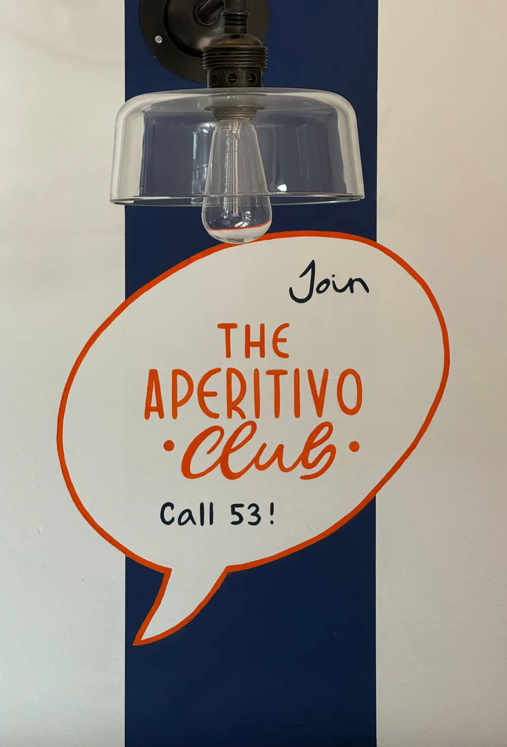 Fumetto «Join the Aperitivo Club» dipinto accanto a una lampada