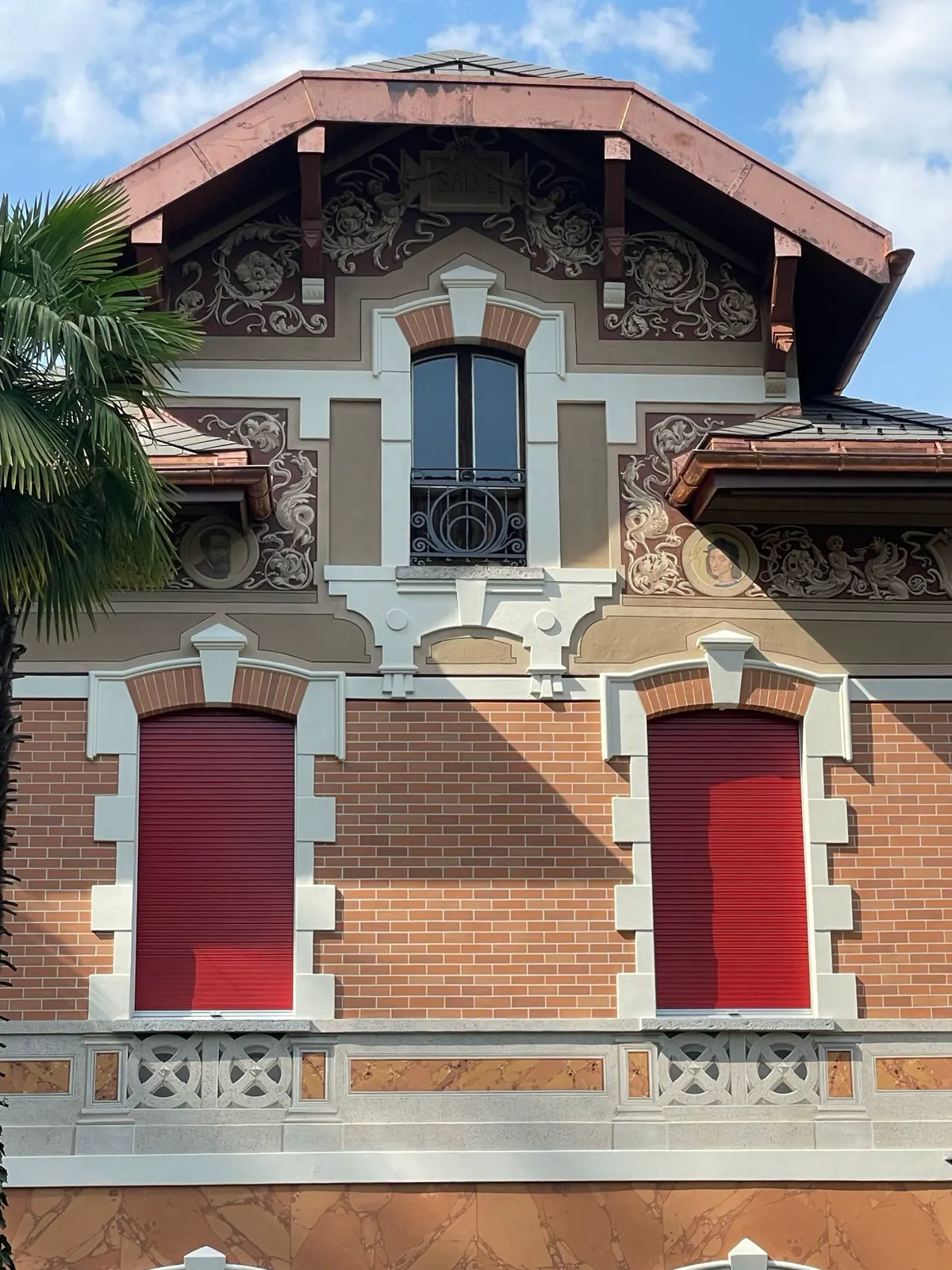 Facciata di villa con mattoni, fregi e medaglioni dipinti sotto il tetto